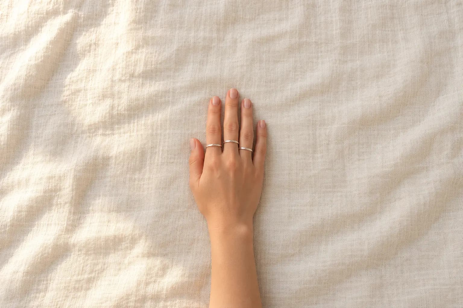 Anillos apilables de plata en una mano, foto horizontal del anuncio
